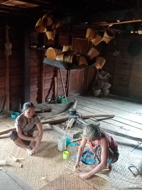 L’équipe au travail : deux femmes tressent au sol dans un atelier.
