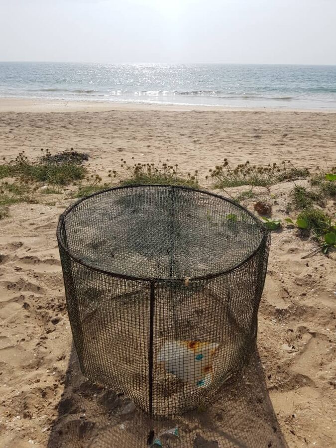 Une cage grillagée protège un nid sur la plage.