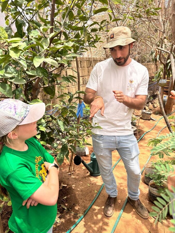 Un animateur explique l’entretien des plants aux enfants au milieu de la pépinière.